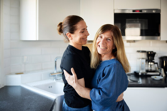 Portrait of happy woman embracing her sister in kitchen at home