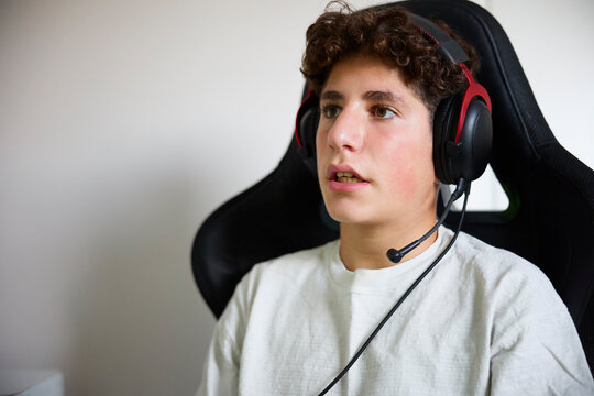 Boy wearing headphones while playing video game at home