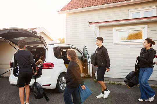 Family helping each other while loading luggage in car trunk