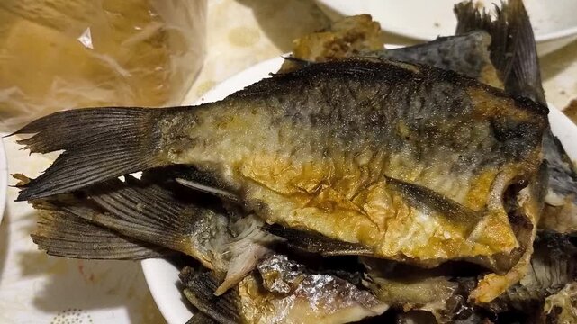 Fried crucian carp breaded in flour on a plate. Benefits of omega 3, vitamins, fatty acids in river fish