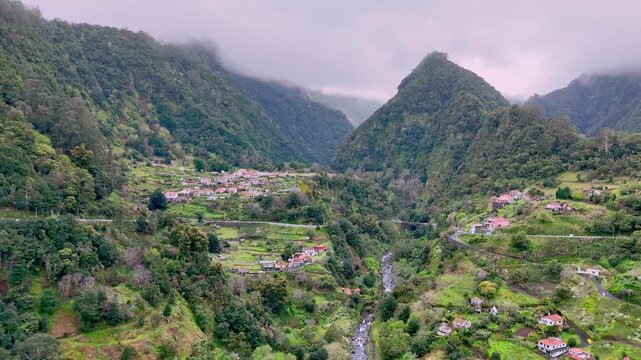 Portugal, Madeira, S&atilde;o Roque do Faial, Ribeira da Metade valley. Nestled deep within a lush volcanic valley, this charming village sits under a blanket of soft mist and towering green peaks. 