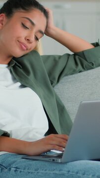 Tired exhausted Indian Muslim woman yawning while using laptop working at home couch studying feeling fatigued overworked low energy insomnia Arabian female girl typing computer distant work indoors