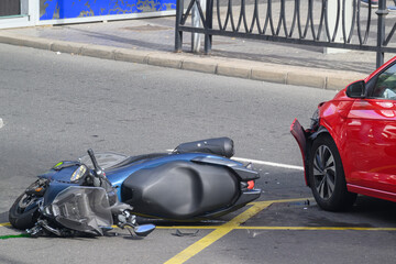 Close up of a car and motorcycle collision showing damage to the front bumper of a red car © ernestorageitos