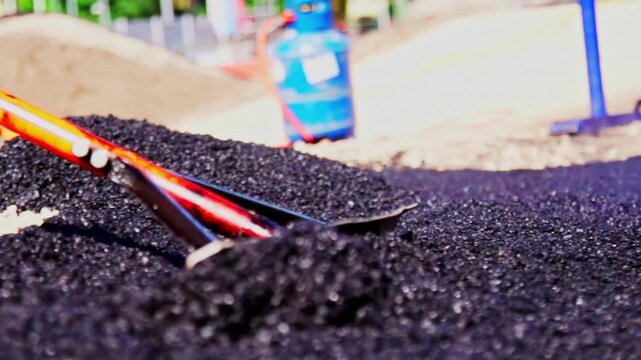 Ground-level view of asphalt being leveled during roadwork, hot tar surface while road renewal