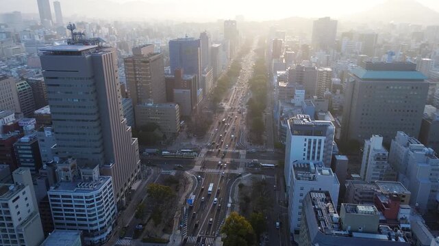 Drone aerial landscape of morning sunrise breaking over urban city buildings along Peace Boulevard main road streets with vehicles and traffic transport in Hiroshima Japan infrastructure and tourism