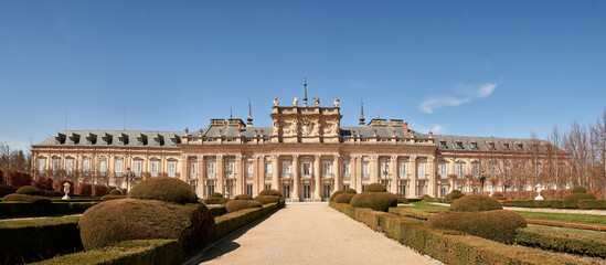 Naklejka premium Wide panoramic view of the Royal Palace of La Granja de San Ildefonso surrounded by formal Baroque gardens in Segovia, Spain. Historic royal residence featuring elegant landscape design