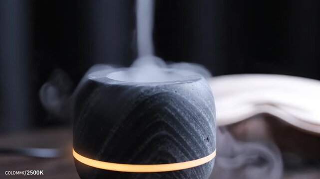 aromatherapy diffuser with cool mist rising and soft amber LED glow. High-end wellness, smart-home tech, and relaxation ritual for Mother's Day. Static macro-utility B-roll.
