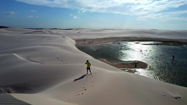 Man runs on desert dunes by lagoon - Lencois Maranhenses, Brazil