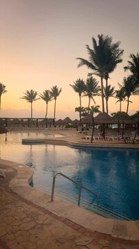 Tropical Resort Swimming Pool with Palm Trees at Sunrise