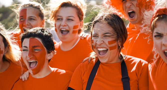 Orange sport fans having fun supporting their team - Football supporters having fun at world cup competition event - Main focus on center girl face
