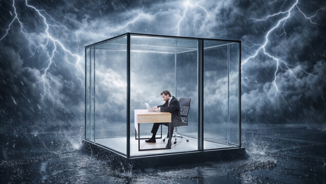Man working on laptop inside glass cube with lightning and storm around it. Concept of high pressure deadlines, performance under stress and stable workflow in extreme conditions.