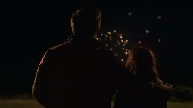Pair Stands Close Together In Wide Field Watching Spectacular Fireworks Illuminate Darkness