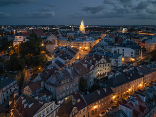 Stare Miasto w Lublinie nocą z oświetlonymi ulicami, Zamkiem i Wieżą Trynitarską, widok z drona © Karol