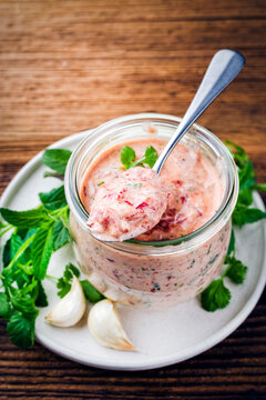 Artisan homemade traditional classic spicy yogurt cacik with garlic ajvar and hot chilli peppers paste and herbs served as close-up in a glass bowl