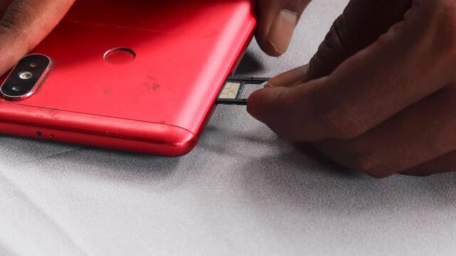 Close-up of male hands inserting, removing and replacing sim card from mobile phone, demonstrating process of changing cellular provider or managing mobile data.
