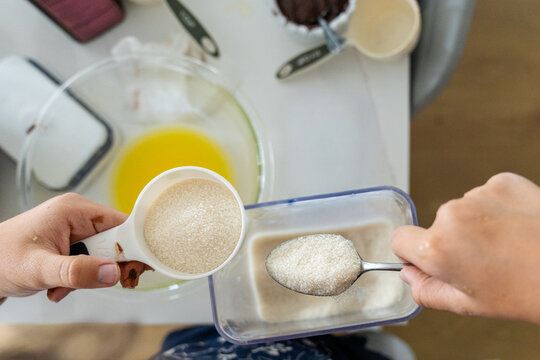 Hands measuring white sugar for homemade brownie recipe in kitchen