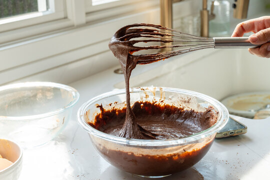 Close up of chocolate brownie batter dripping from whisk into bowl