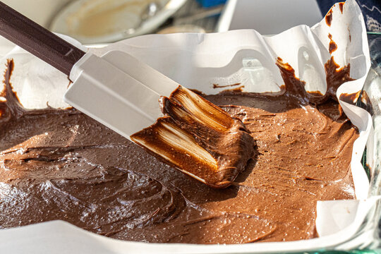  Spreading chocolate brownie batter in pan with rubber spatula close up