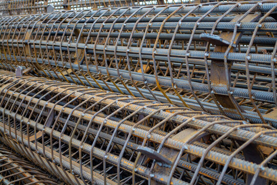 Metal rebar cage for concrete reinforcement stack at construction site. Industrial framing skeleton for foundation support. Heavy duty building material for civil engineering structure.