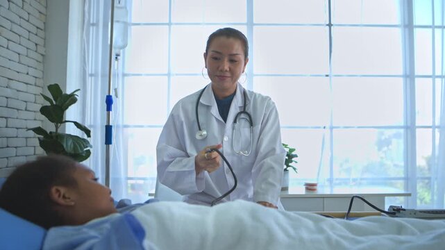 Doctor preparing blood pressure monitor for young inpatient in hospital ward, emphasizing continuous medical monitoring
