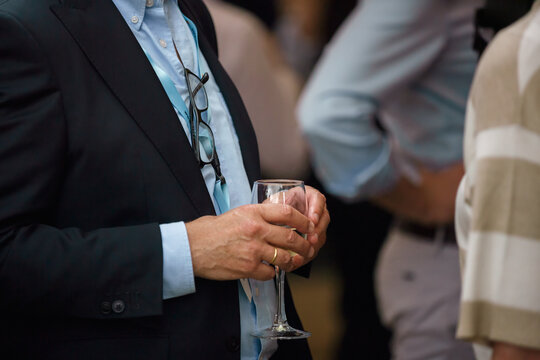 Close-up of a business event guest holding a champagne glass during a corporate reception or networking gathering.