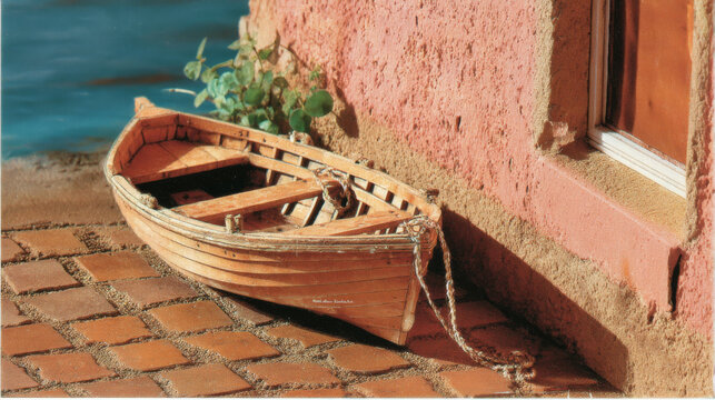 Detailed Miniature Wooden Rowboat on a Cobblestone Waterfront Pier