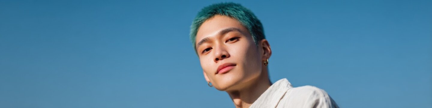 Asian male young teal buzzcut outdoor portrait strong jawline confident look minimal clothes blue sky background