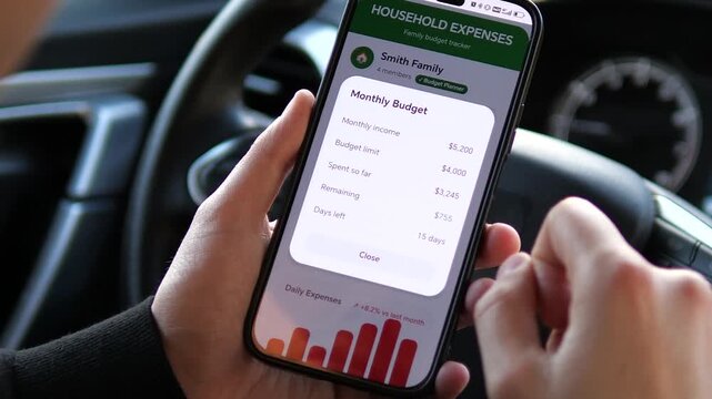 Close-up of a person tracking household expenses on a smartphone while in a car. Managing monthly budget, income, and spending through a sleek fintech app. Perfect for finance, banking, and personal