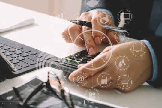 close up of businessman hand working with finances about cost and calculator and latop with mobile phone on withe desk in modern office with VR icon diagram