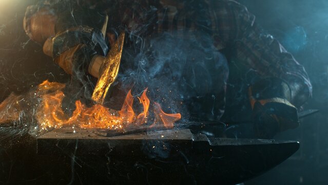 Close-up of blacksmith forging glowing hot iron on anvil with flying sparks