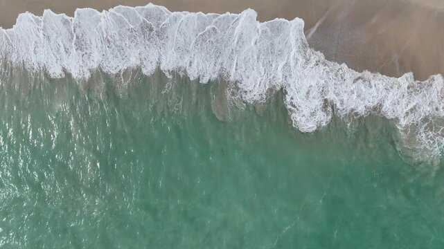 Aerial View of Turquoise Ocean Waves Crashing on Sandy Beach from Above