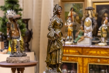Fototapeta premium Vintage metal figurine of a woman. Metal small antique statuette of a woman in an antique shop. Antique statuette in the store. Antique jewelry.