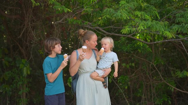 Young mom spending quality time with her two sons in a lush green park, enjoying nature, laughter, and joyful family bonding moments outdoors.