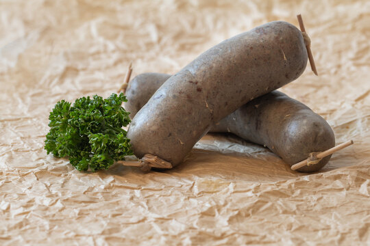 Traditional Czech white pudding sausages on parchment paper with a halved onion, natural daylight on a white background, artisan style