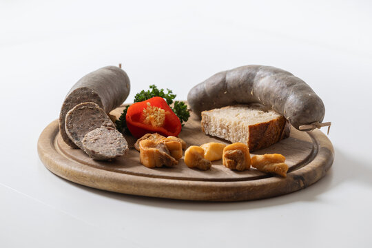Traditional Czech pork liver sausages (jitrnice), crispy rinds, and fresh bread on a wooden board. Rustic food photography, white background.
