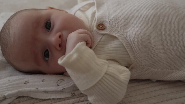 Close up of newborn baby girl sucking her fist self soothing behavior of infant natural development moment soft lighting