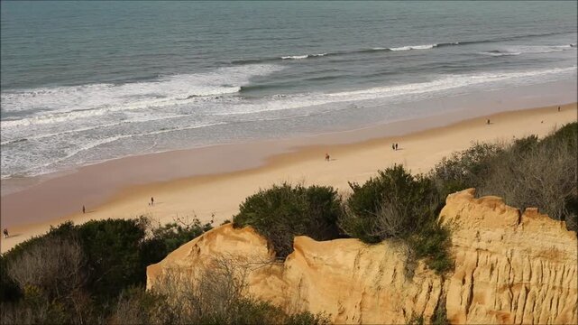 Dramatic orange sandstone cliffs meet the ocean with a sandy beach below