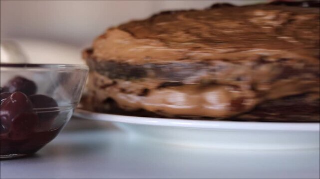 Delicious homemade chocolate cake with creamy frosting and cherries on the side