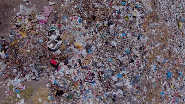 Aerial view of people collecting waste in a landfill with dense garbage accumulation. Scene highlights environmental pollution, waste management, recycling, and human labor.