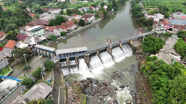 An aerial drone perspective reveals the historic Katulampa Dam spanning the Ciliwung River in Bogor