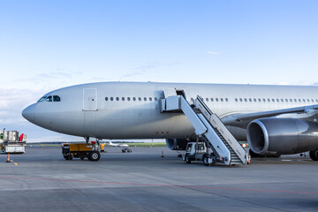 Fototapeta premium Close-up of the wide body passenger plane with stairway at the airport