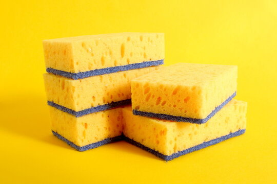 Several porous dishwashing sponges lie on a yellow background.