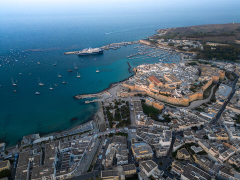 Aerial view of the historic coastal town of Otranto featuring the Aragonese Castle, the harbor with numerous boats, and the turquoise waters of the Adriatic Sea Otranto, Apulia, Italy.