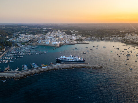 Aerial view of the historic coastal town and harbor with a large cruise ship and numerous boats at sunset Otranto, Apulia, Italy.