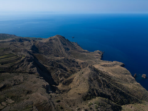 Aerial view of the rugged volcanic landscape and steep cliffs of the Aeolian Islands overlooking the deep blue Mediterranean Sea in Sicily, Italy.