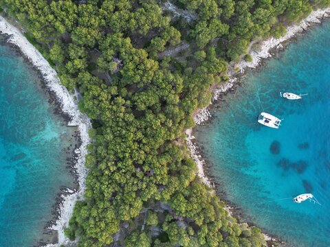 Aerial top-down view of narrow forested isthmus between two turquoise bays with sailboats, Pa&scaron;man Island, Dalmatian Coast, Croatia