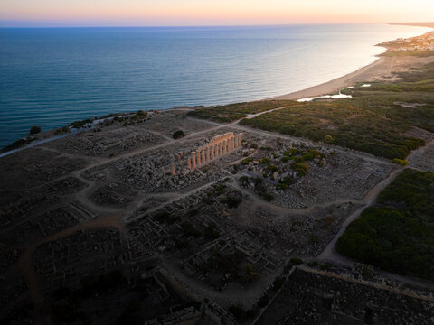 Aerial view of the ancient Greek temple ruins in Selinunte Archaeological Park along the Mediterranean coast at sunset in Marinella, Sicilia, Italy.