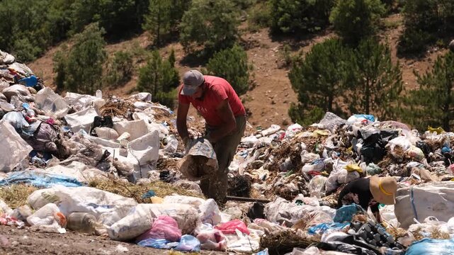 Two people collecting waste in an open landfill area. Realistic scene highlighting environmental pollution, recycling, sustainability, and environmental awareness themes.