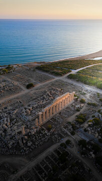 Aerial view of the ancient Greek ruins of Selinunte Archaeological Park featuring Temple C and stone columns overlooking the Mediterranean Sea at sunset Marinella, Sicilia, Italy.