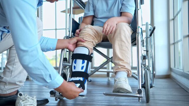 Father adjusting orthopedic ankle brace for young boy in wheelchair, highlighting family support and rehabilitation care